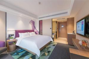 1 dormitorio con 1 cama blanca grande y TV en Hampton by Hilton Zhengzhou High-Tech Zone en Zhengzhou