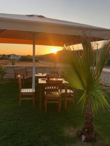 a table and chairs under an umbrella with the sunset at Ersin Konak in Bozcaada