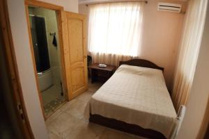 a small bedroom with a bed and a shower at Hotel Kiparis in Pizunda