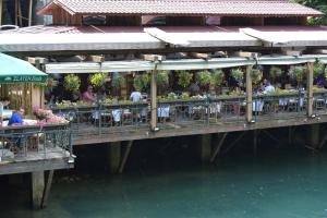 a pier with people sitting at tables on the water at Canyon Matka Hotel in Matka