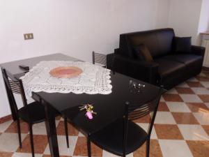 un tavolo nero con sedie, una sedia, un tavolo e un divano di Residenza Graziella a Cavedago
