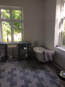 uma casa de banho com uma banheira, um lavatório e uma janela em Liebacksgården em Skegrie