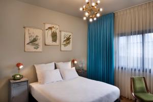 a bedroom with a large bed and a blue curtain at Dave Gordon, a member of Brown Hotels in Tel Aviv