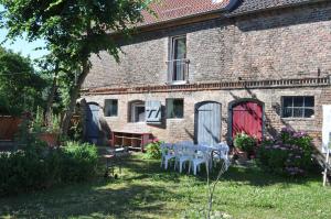 a brick house with tables and chairs in the yard at Kulturfreizeiten Ferienwohnungen in Neuruppin