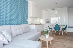 a living room with a white couch and a kitchen at Unique 3City Apartments - Sea Apartment in Gdańsk