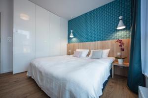 a bedroom with a large white bed and a blue wall at Unique 3City Apartments - Sea Apartment in Gdańsk