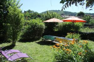 a garden with two umbrellas and a table and chairs at Cantal'Envie in Massiac