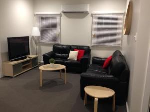 a living room filled with furniture and a tv at Colonial Lodge Motor Inn in Yass