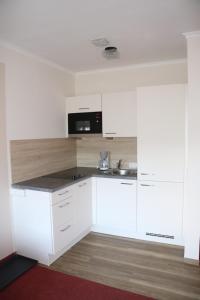 una cocina vacía con armarios blancos y microondas en Pension Bichlgeiger, en Anras