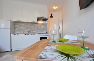 a kitchen with a wooden table with two wine glasses at Suitable Summer Apartments in Pula