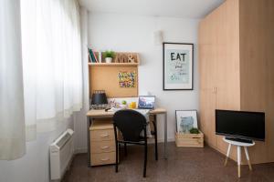 um escritório com uma secretária com uma cadeira e uma televisão em Residencia Universitaria Colegio de Cuenca em Salamanca