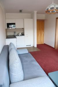 Una sala de estar con un sofá y una cocina. en Pension Bichlgeiger, en Anras