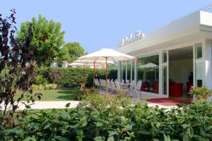 eine Terrasse mit Stühlen und einem Sonnenschirm in einem Garten in der Unterkunft Hotel Bahama in Rimini