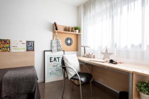 a desk with a chair in a room with a window at Residencia Universitaria Colegio de Cuenca in Salamanca