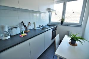 cocina blanca con fregadero y mesa en Exclusive Apartment Cologne, en Colonia