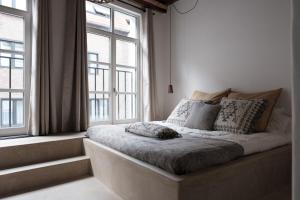 a bed sitting in a room with two windows at Boutique Holiday Home ZaligInAntwerpen 77 in Antwerp