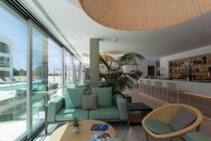 a hotel lobby with a green couch and chairs at Sa Pedrera Suites & Spa in Es Pujols