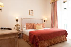 a bedroom with a bed and a desk and a window at Hotel Real Palacio in Lisbon