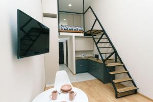 ein Wohnzimmer mit einer Treppe, einem TV und einer Küche in der Unterkunft Dvukhurovnevyi liuks na Beresteiskoi in Kiew