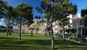 a building in a park with trees in the foreground at NAU Sao Rafael Suites - All Inclusive in Albufeira