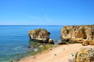 a group of people on a beach near some rocks at NAU Sao Rafael Suites - All Inclusive in Albufeira