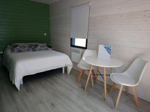 Un dormitorio con una cama y una mesa y sillas. en Au Cap Norwoe, en Saint-Quentin-en-Tourmont