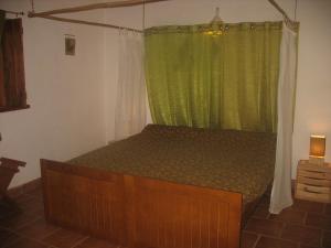 1 dormitorio con 1 cama con cortina verde en Monte da Gravita, en Ribeira do Salto