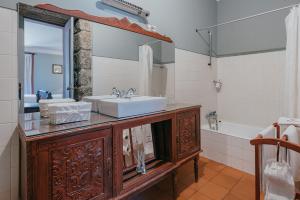 La salle de bains est pourvue d'un lavabo, d'un miroir et d'une baignoire. dans l'établissement Casa Dos Pombais, à Guimarães