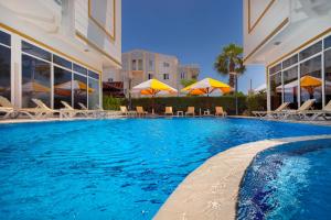 a swimming pool with chairs and umbrellas next to a building at Golden Orange Hotel in Antalya