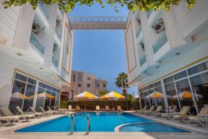 a swimming pool in front of a building with chairs and umbrellas at Golden Orange Hotel in Antalya