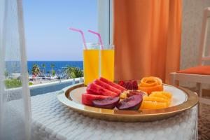 a plate of fruit on a table with a drink at Golden Orange Hotel in Antalya