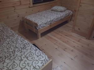 two beds in a room with wooden floors at Шале Озера in Melʼniki