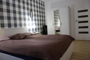 sypialnia z łóżkiem i ścianą szachownicą w obiekcie Apartament Solna 106 w Kołobrzegu