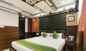 a bedroom with a large bed with a black headboard at Hotel Dvaraka Inn in Bengaluru