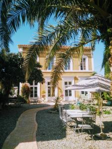 una casa con mesa, sillas y sombrilla en La Maison des Palmiers en Homps