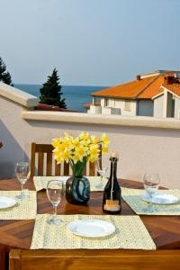 a wooden table with yellow flowers and a bottle of wine at Rooms and Apartments Villa Dama in Pula