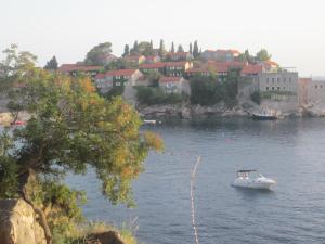 a small boat in a body of water with a town at Apartments Danilo Kažanegra in Sveti Stefan