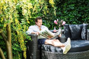 Un uomo seduto su una sedia a leggere un giornale di Hotel Elisabetha Garni ad Hannover