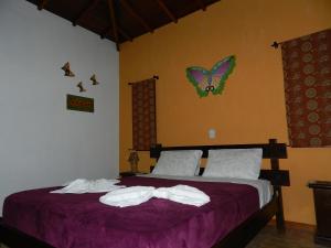 a bedroom with a purple bed with butterflies on the wall at Pousada Cheiro de Mato in Monte Alegre do Sul