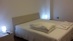 1 dormitorio con 1 cama con sábanas blancas y 2 luces en Peri Peri Holiday Home - Siracusa, en Solarino