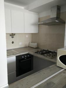 a kitchen with white cabinets and a stove top oven at Maresol in Costa da Caparica