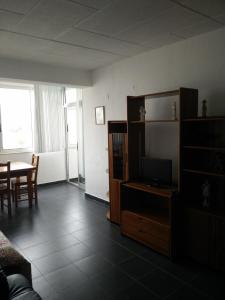 ein Wohnzimmer mit einem TV und einem Esstisch in der Unterkunft Maresol in Costa da Caparica