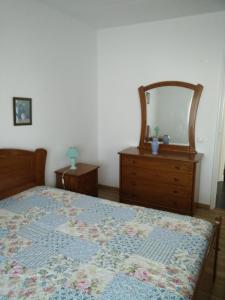 Schlafzimmer mit einem Bett, einer Kommode und einem Spiegel in der Unterkunft Maresol in Costa da Caparica