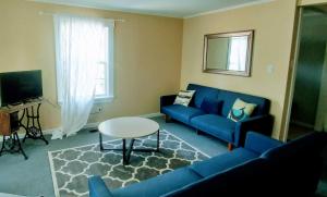 a living room with a blue couch and a table at Steps to the Waterfront in Shelburne