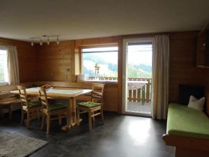 een eetkamer met een tafel en stoelen en een balkon bij Ferienhaus Nussbaumer in Sibratsgfäll