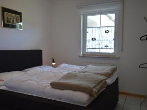 un letto con una coperta in una stanza con finestra di Cosy holidayhome near the forest a Zendscheid