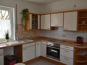 una cucina con armadi bianchi, lavandino e piano cottura di Cosy holidayhome near the forest a Zendscheid