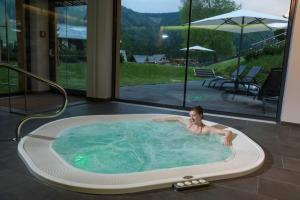 una donna sdraiata in una vasca idromassaggio in una casa di Hotel Teichwirt a Fladnitz an der Teichalm