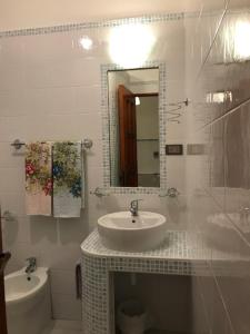 uma casa de banho branca com um lavatório e um espelho em Residenza Luna em Paestum