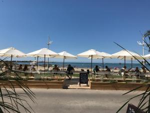 people sitting at tables with umbrellas at the beach at Hôtel Café Miramar in Le Grau-du-Roi
